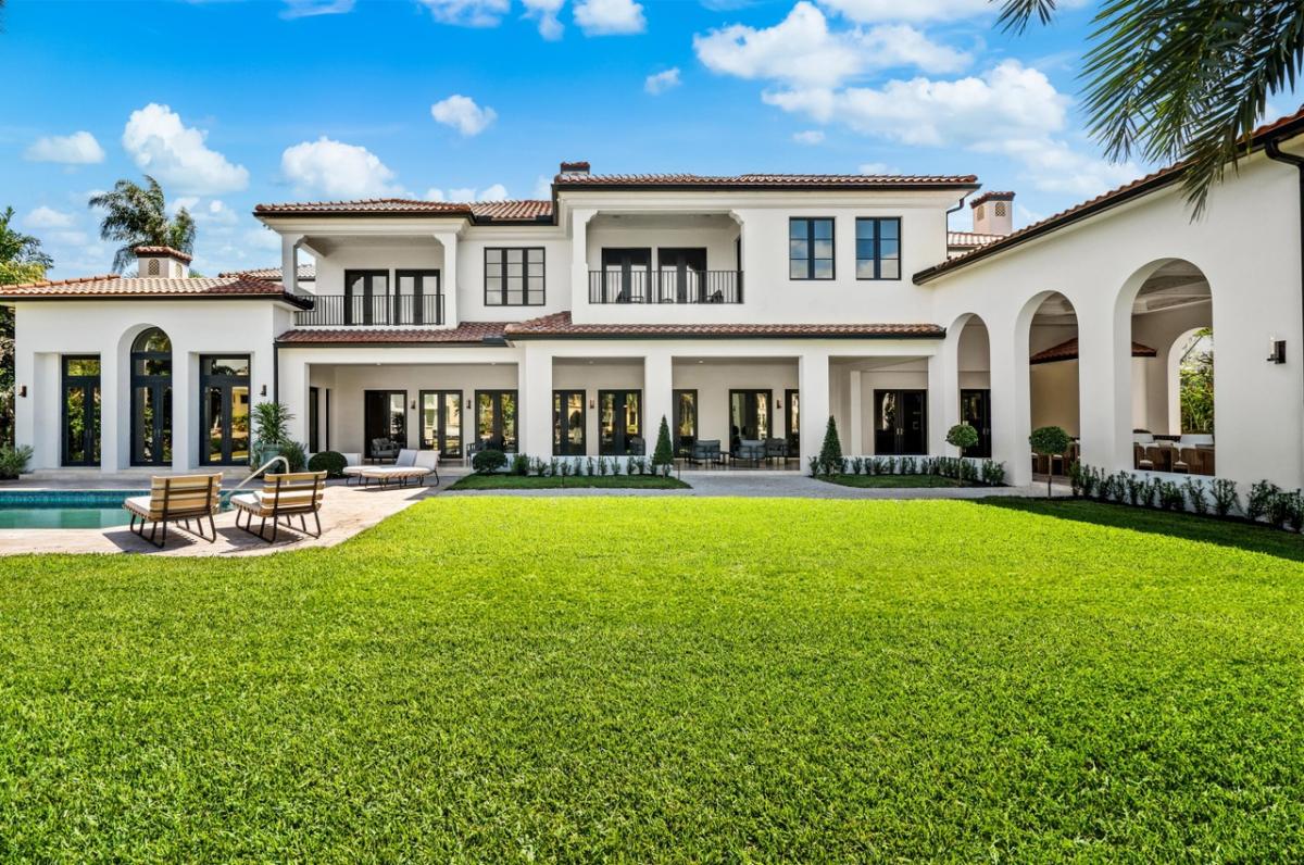 Rear view of the mansion with a pool and a large green lawn.