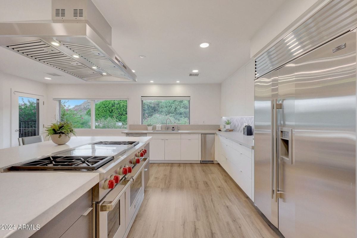 A kitchen with countertops, cabinets, windows, and kitchen appliances.