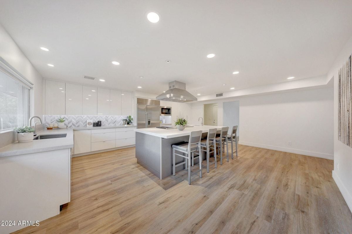 A kitchen with countertops, chairs, cabinets, and a sink.