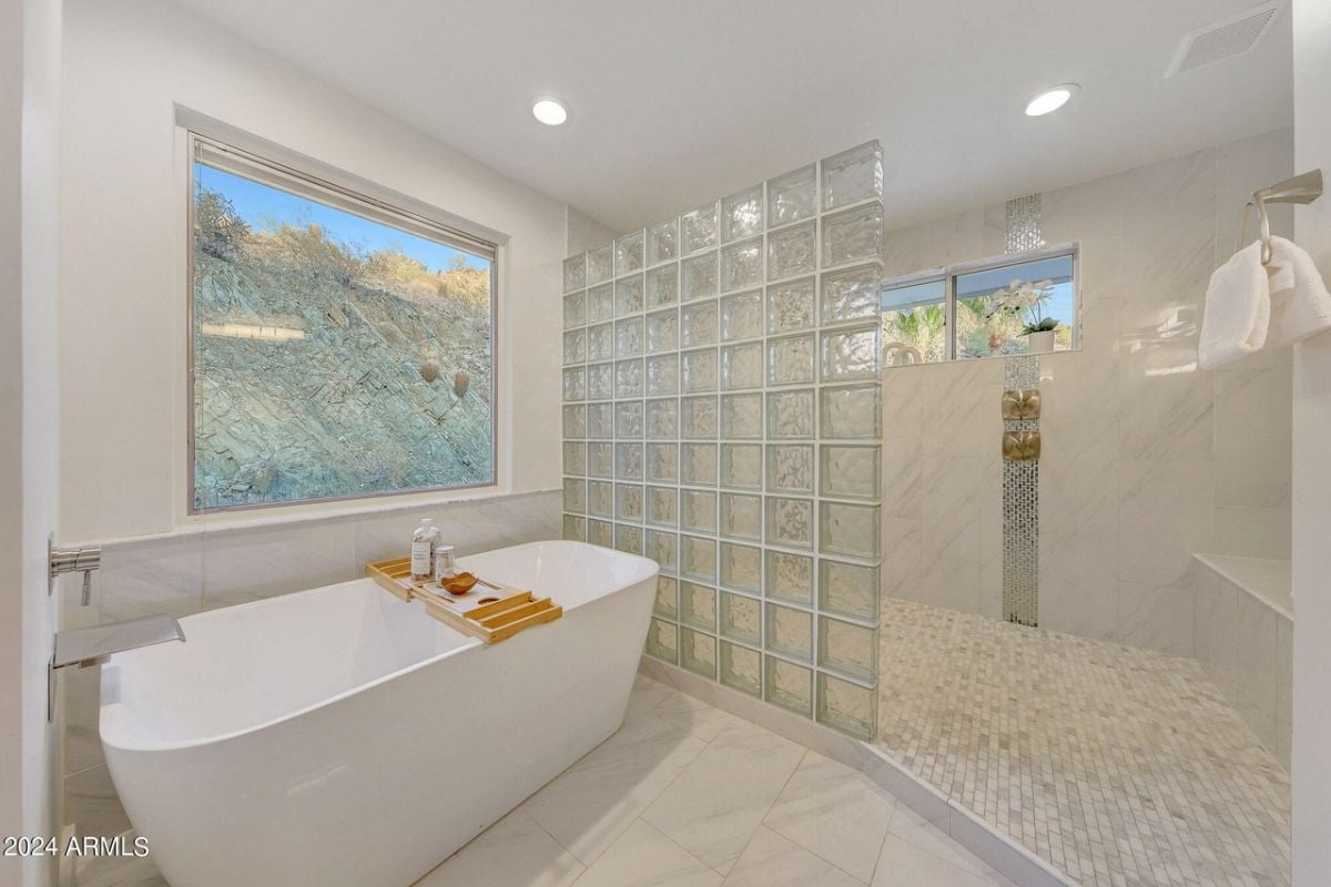 A bathroom with a window, bathtub, and shower.