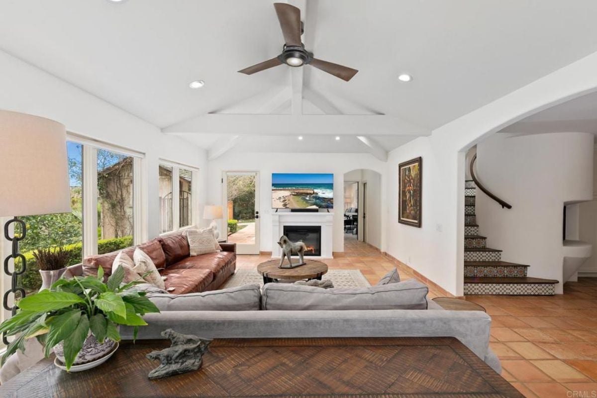 A living room with a ceiling fan, TV, fireplace, couches, and a center table.