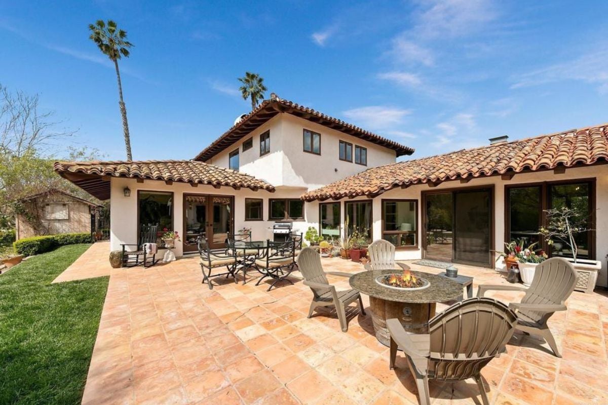 A patio with a table and a fire pit surrounded by chairs.