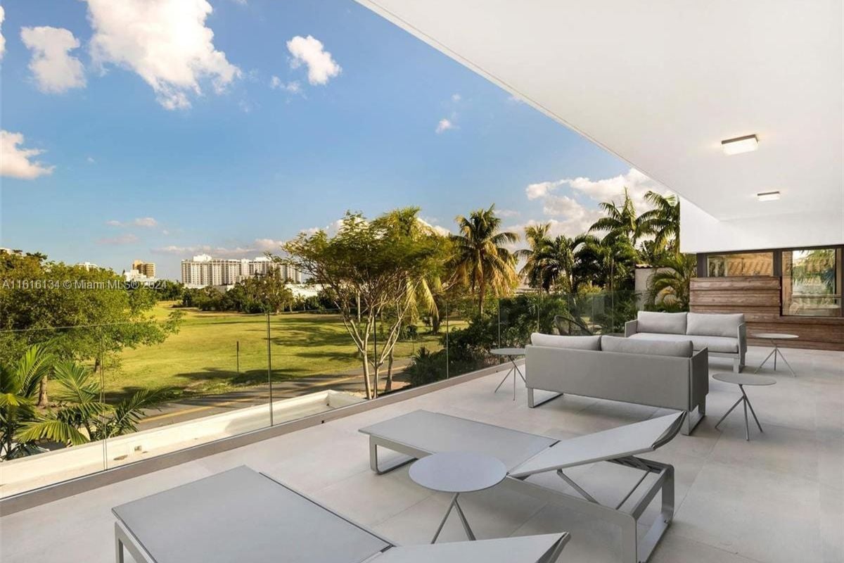 A terrace with chairs, couches, and coffee tables.