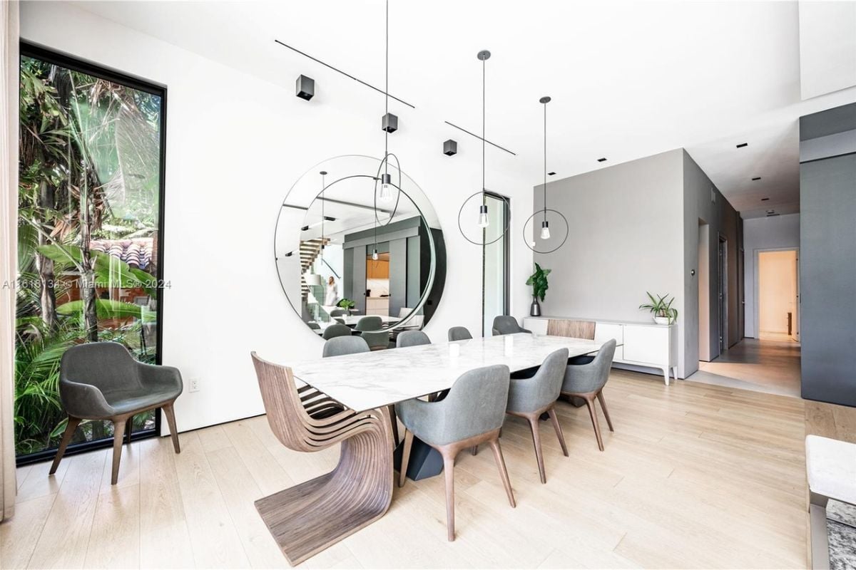 A dining area with a mirror and a dining table surrounded by chairs.
