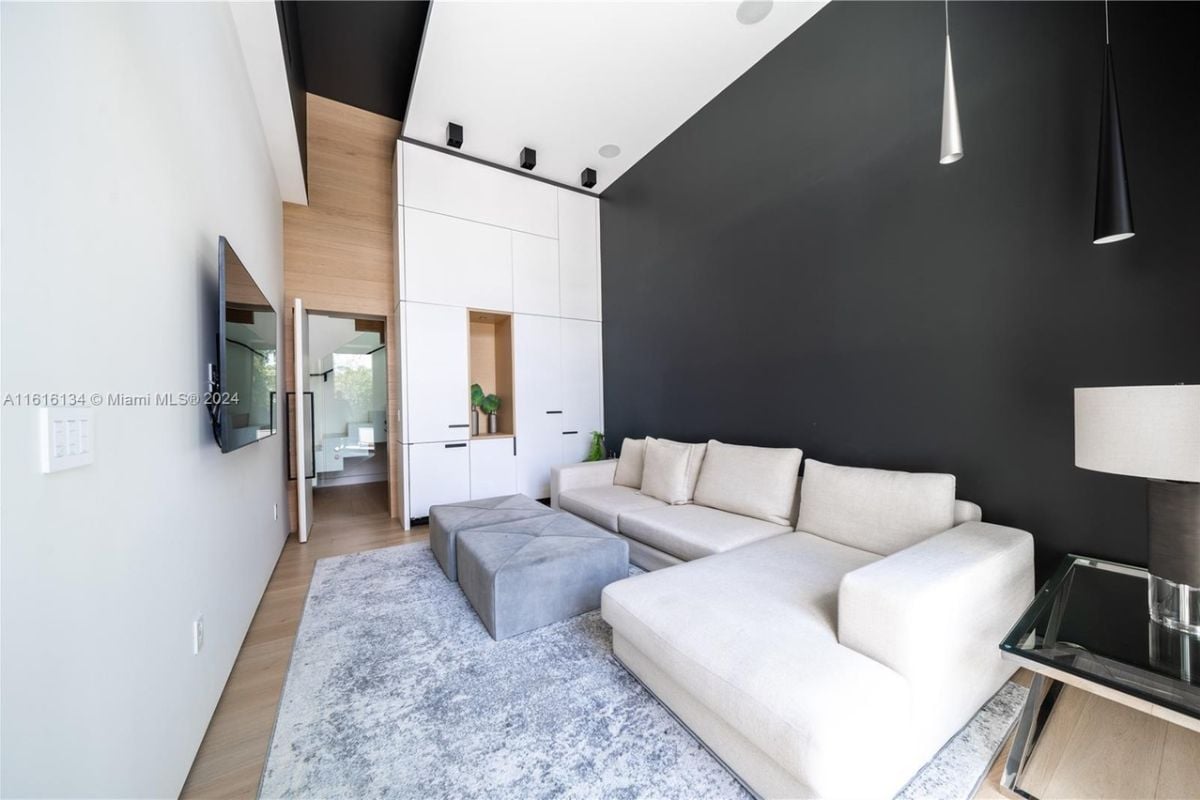 A sitting area with a TV and a white couch with pillows.