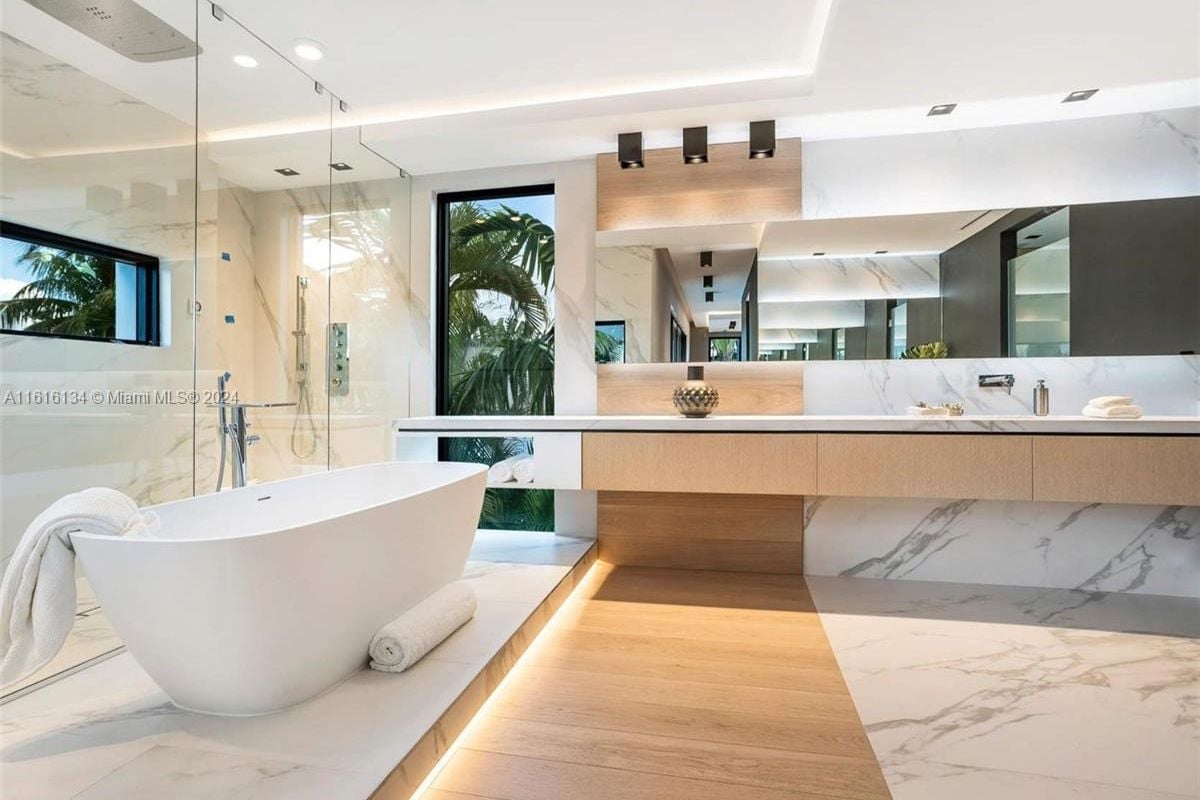 A bathroom with a countertop, mirror, bathtub, and shower room.