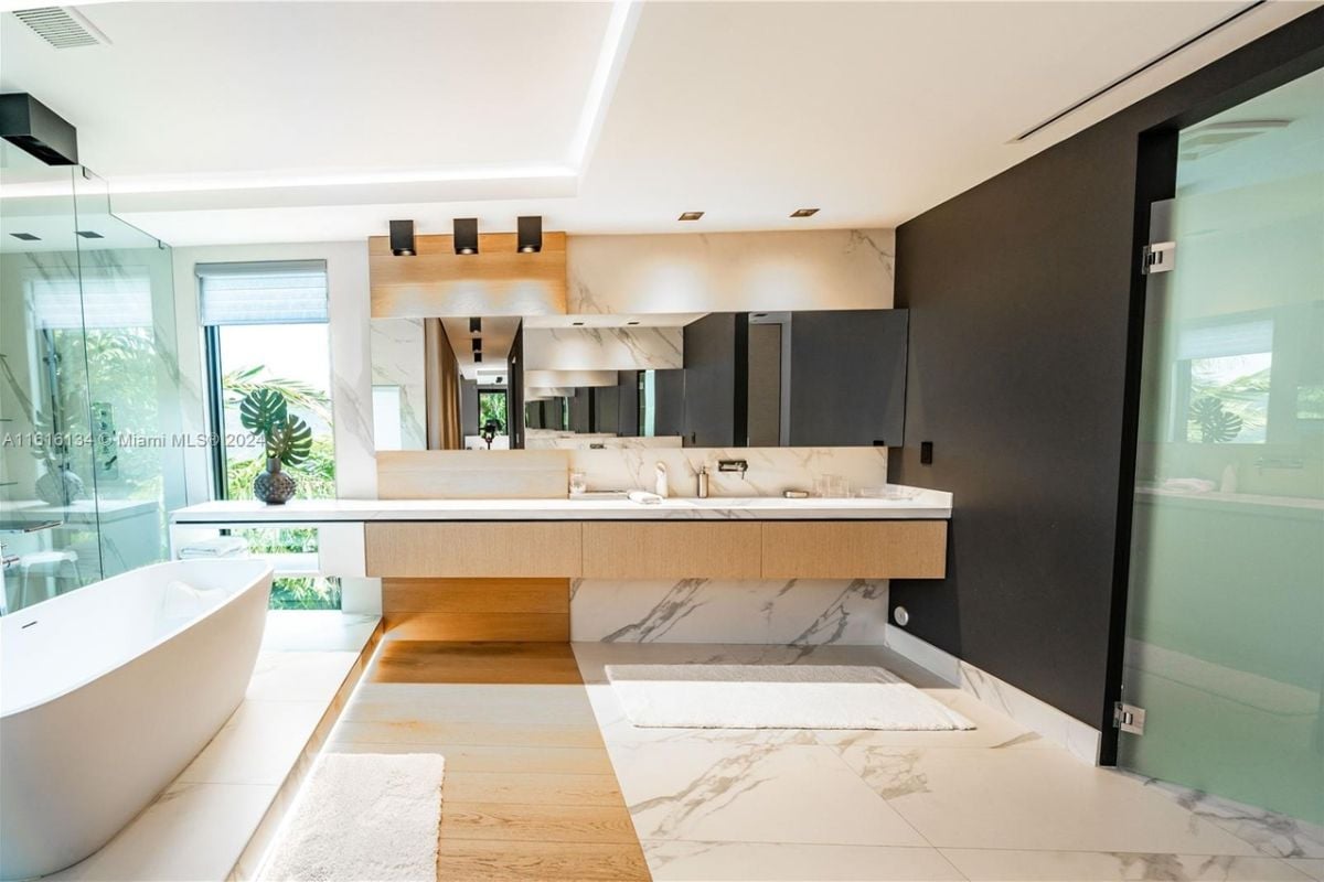A bathroom with a countertop, mirror, bathtub, and shower room.
