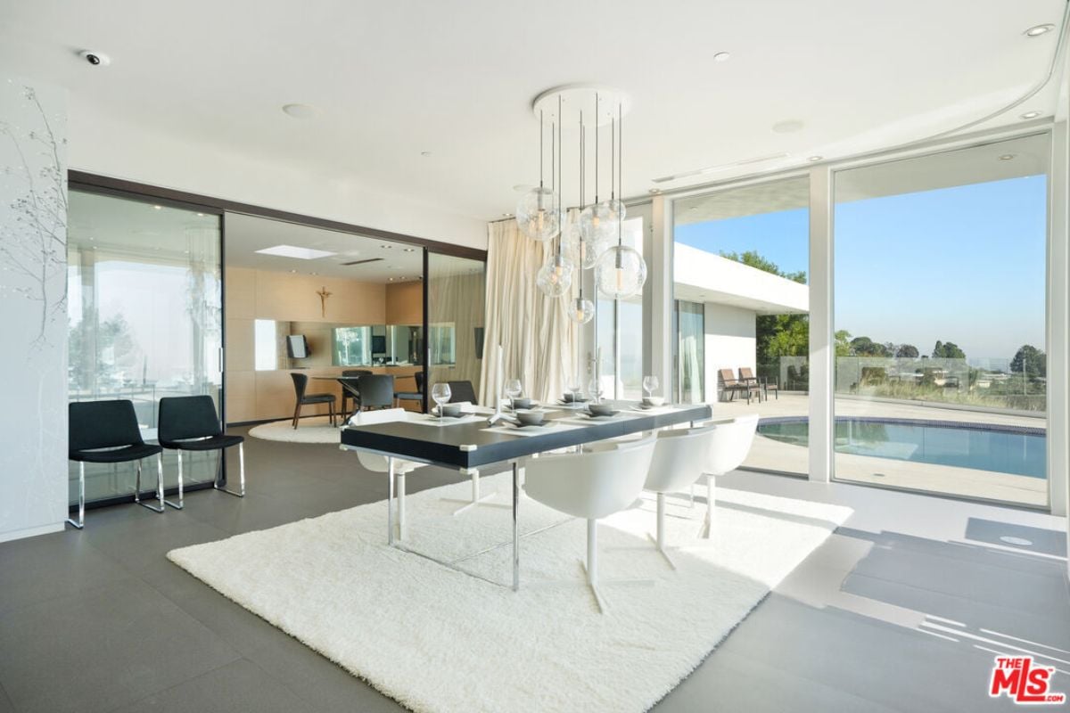 A dining room with a rug, chairs, and a dining table surrounded by chairs.