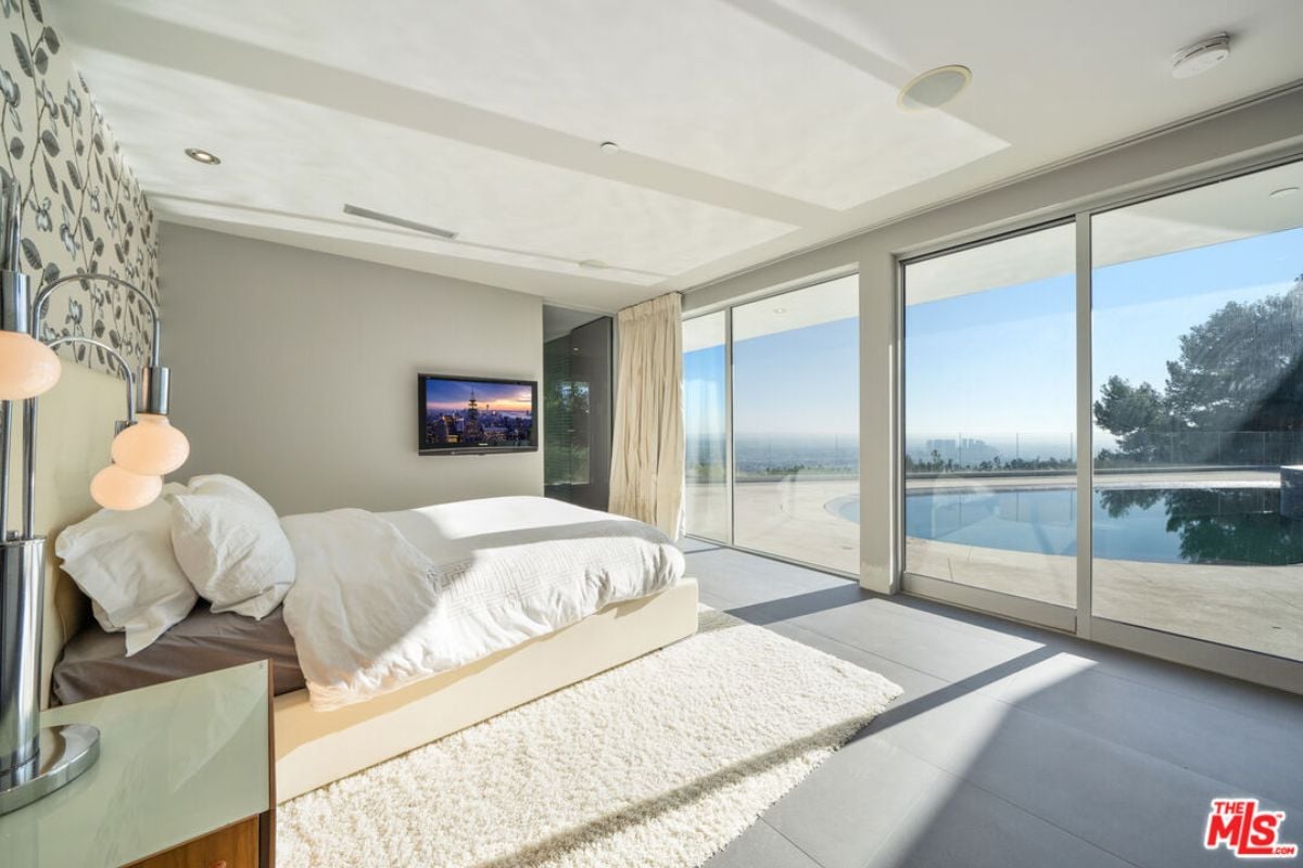 A bedroom with a bed, TV, nightstand, and rug.