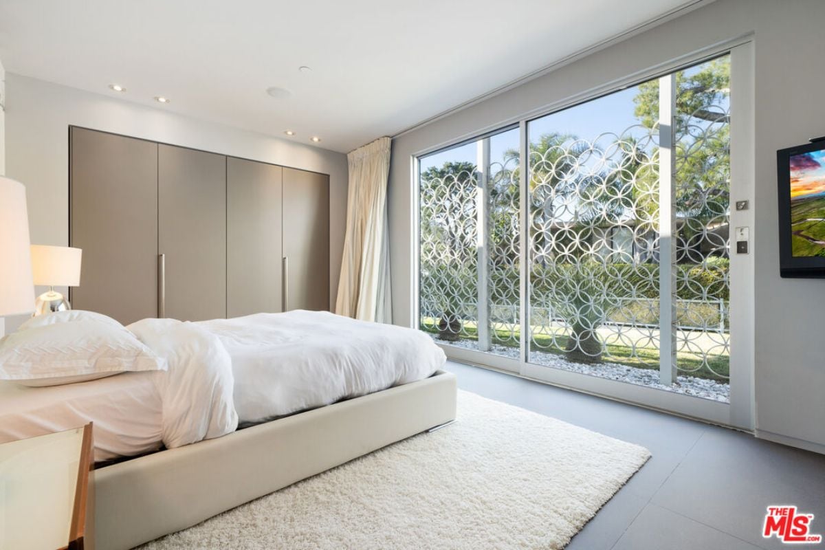 A bedroom with a bed, TV, nightstand, and rug.