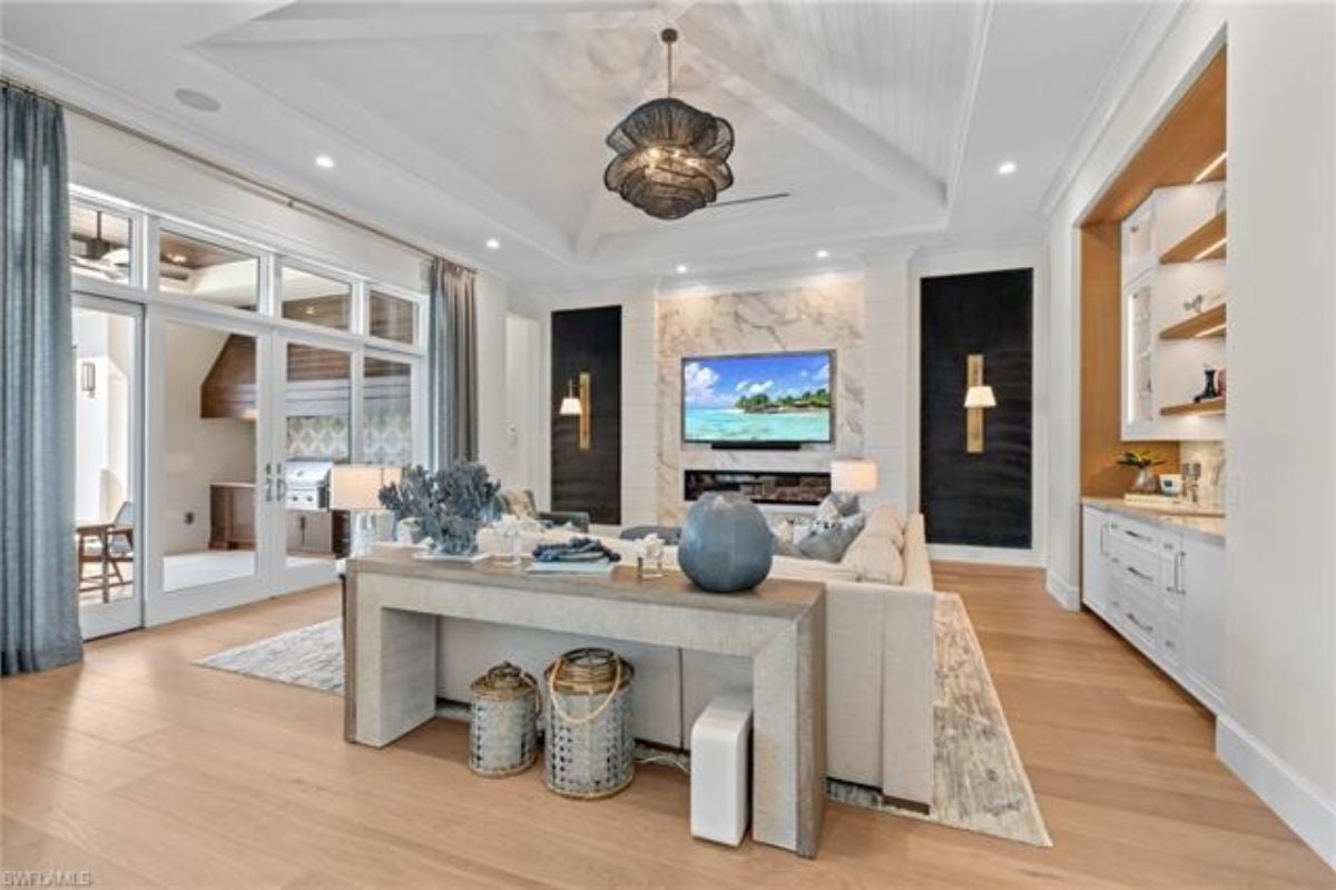 A living room with a chandelier, shelves, cabinets, a TV, and couches.