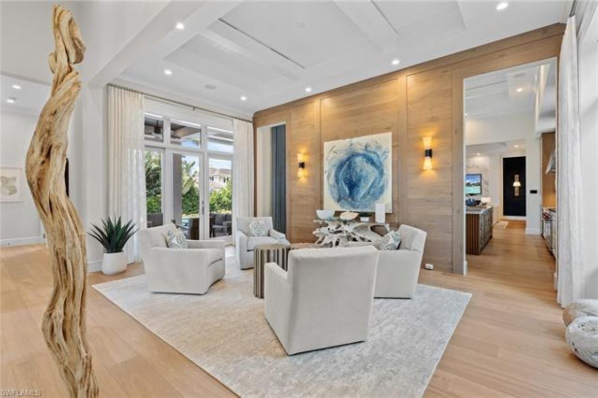 A living room with a painting, a rug, and a coffee table surrounded by chairs.