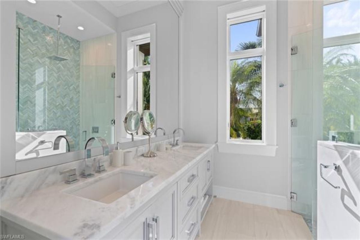 A bathroom with dual vanities, cabinets, and a mirror.