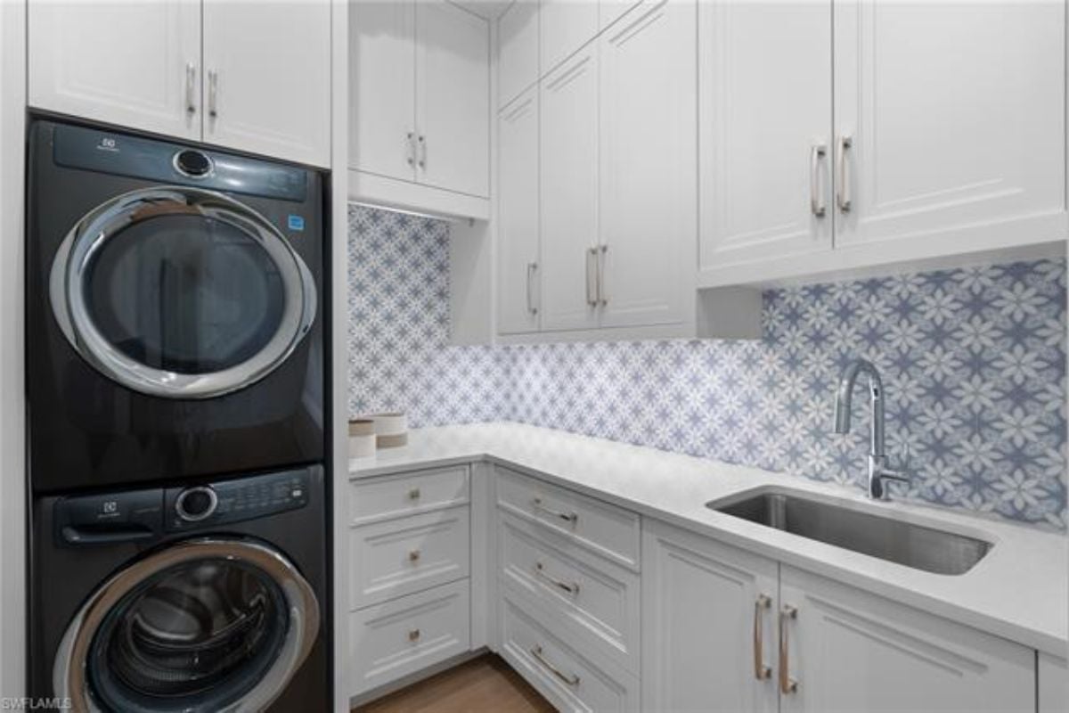 A laundry room with a countertop, sink, cabinets, and a washing machine.