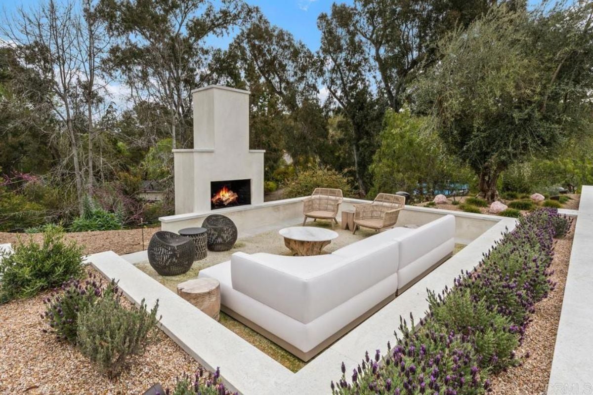 A patio with a fireplace, couch, chairs, and coffee table.