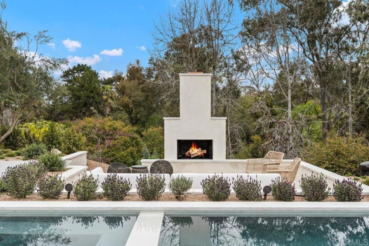 A patio with a fireplace, couch, chairs, and coffee table.