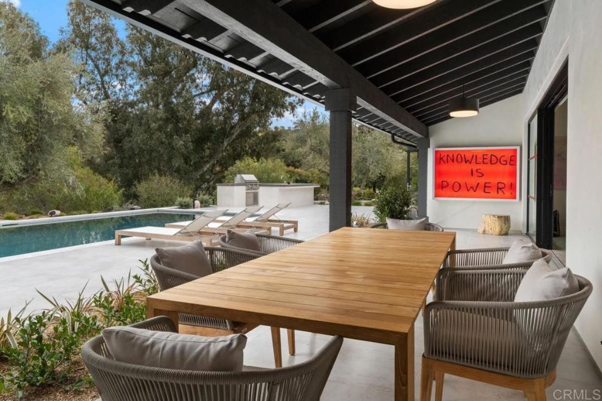 A porch with a table surrounded by chairs.