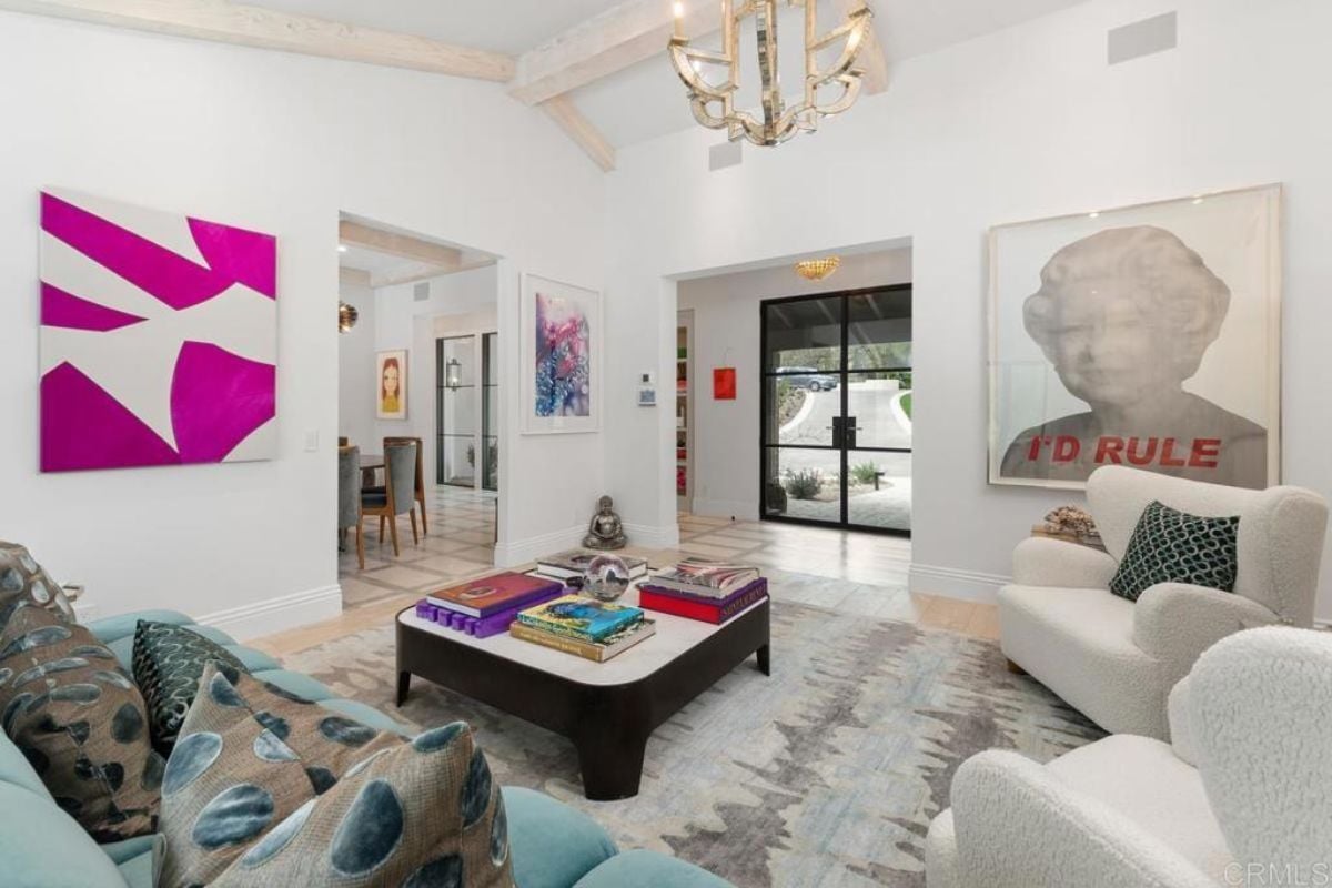 A living room with a chandelier, paintings, couches, rug, and a center table.