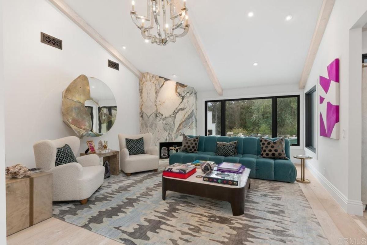 A living room with a chandelier, paintings, couches, rug, and a center table.