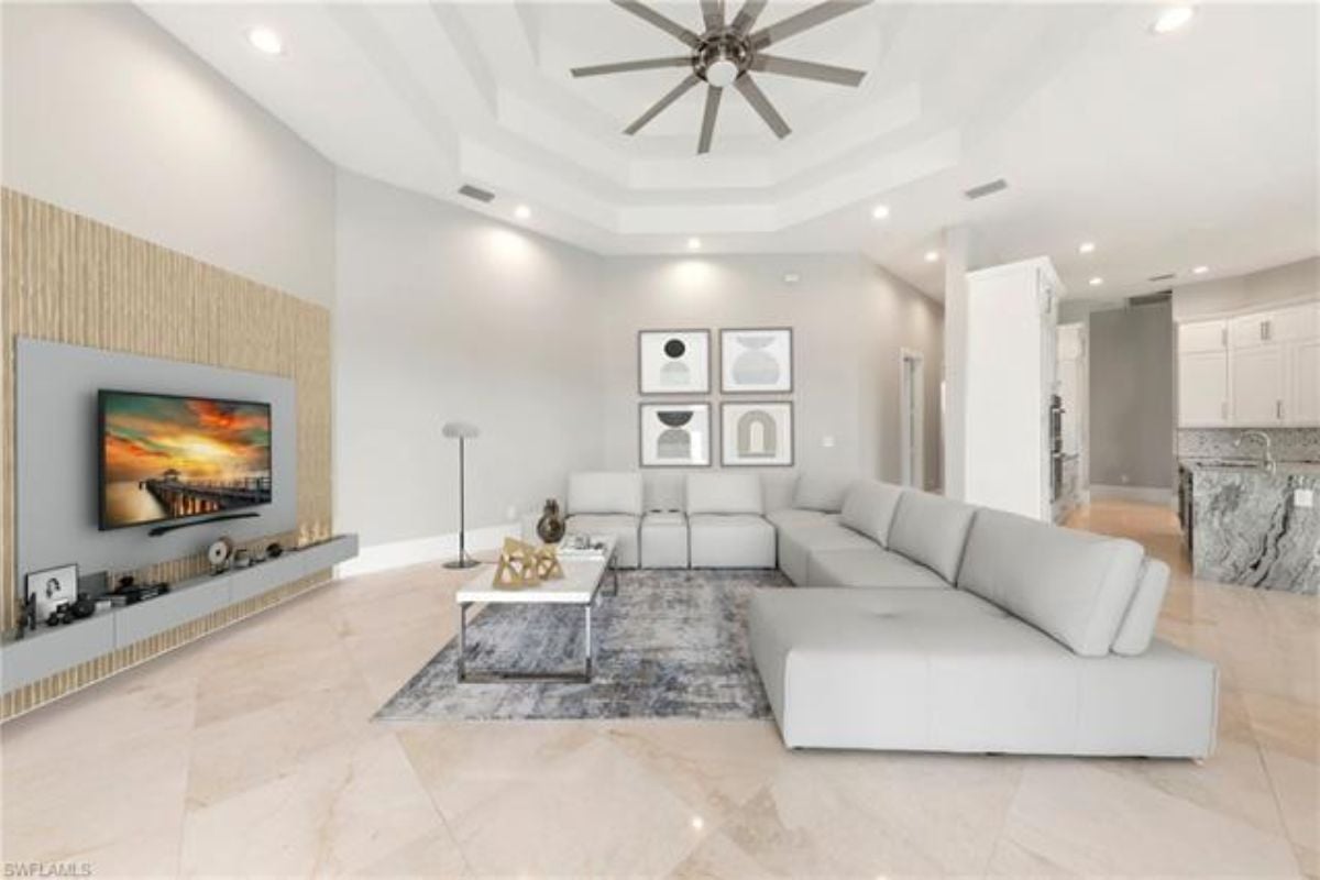 A living room with a ceiling fan, TV, tiled floor, couch, and a center table.