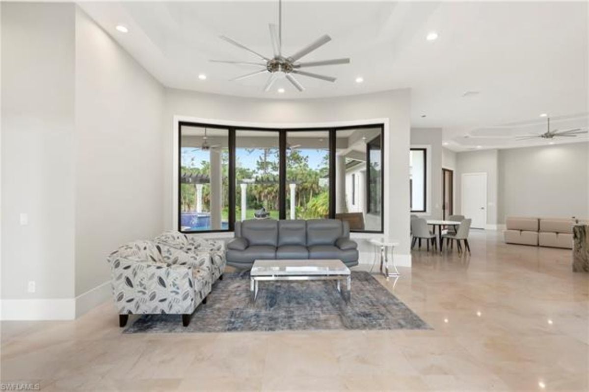 A living room with a ceiling fan, tiled floor, couch, and a center table.