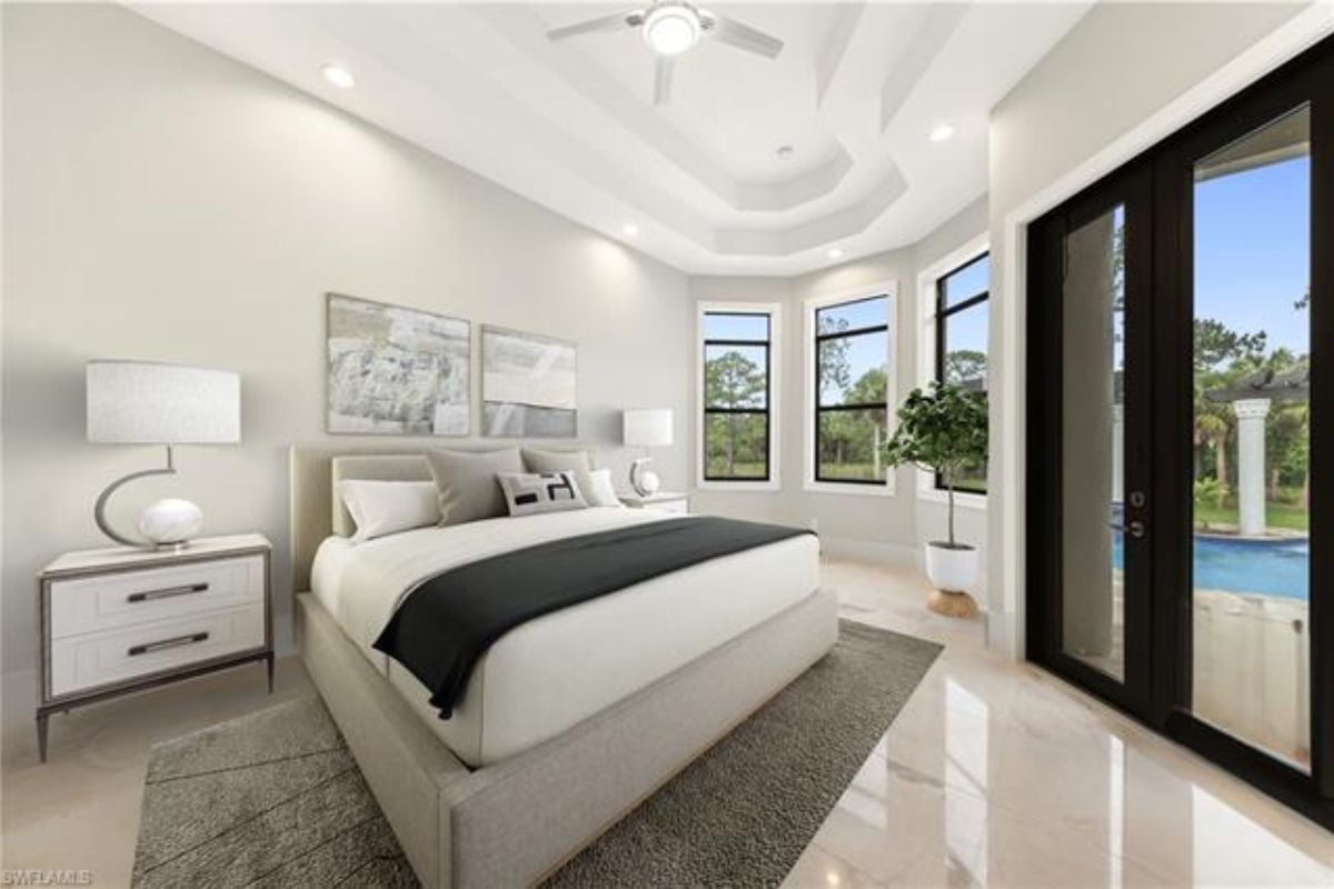 A bedroom with a bed, nightstand, rug, windows, and a ceiling fan.