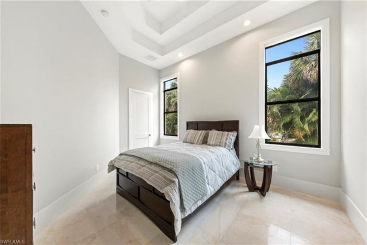 A bedroom with a bed, windows, and a nightstand.
