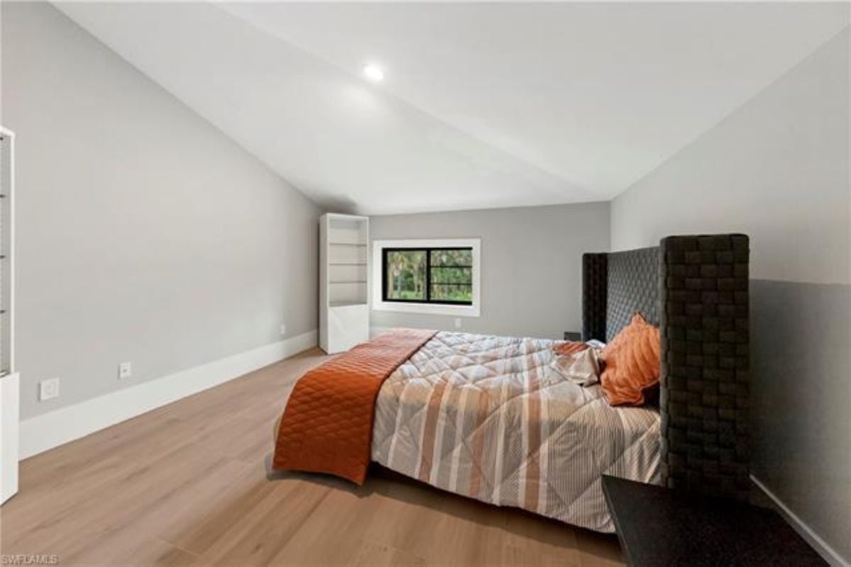 A bedroom with a bed, a window, and a shelf.