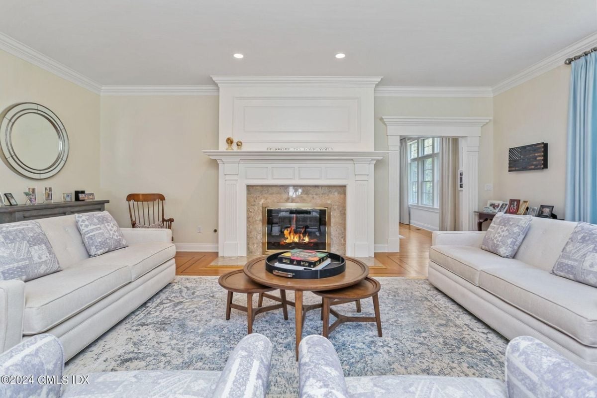 The living room includes a fireplace, rug, couches, and a center table.