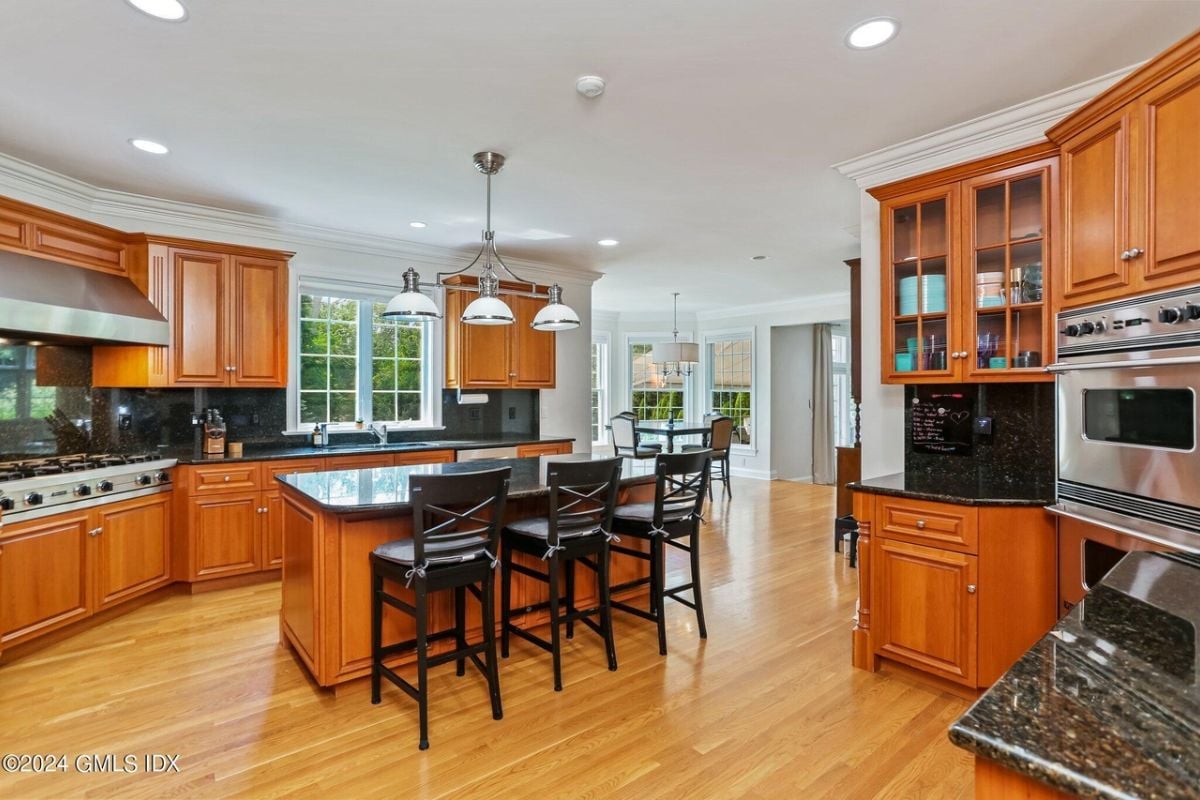 The kitchen features a center island, chairs, countertops, cabinets, and kitchen appliances.