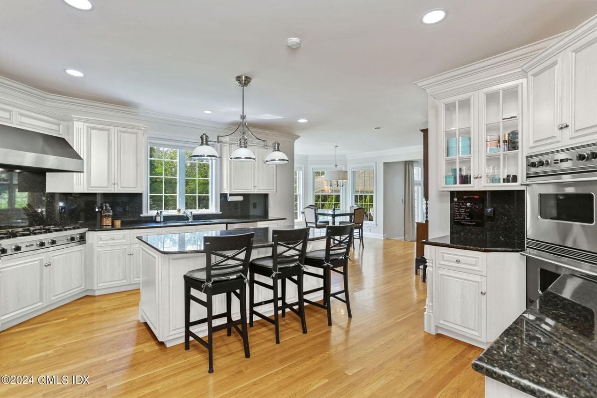 The kitchen features a center island, chairs, countertops, cabinets, and kitchen appliances.