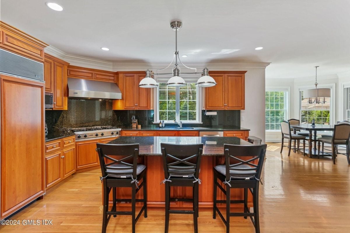 The kitchen features a center island, chairs, countertops, cabinets, and kitchen appliances.