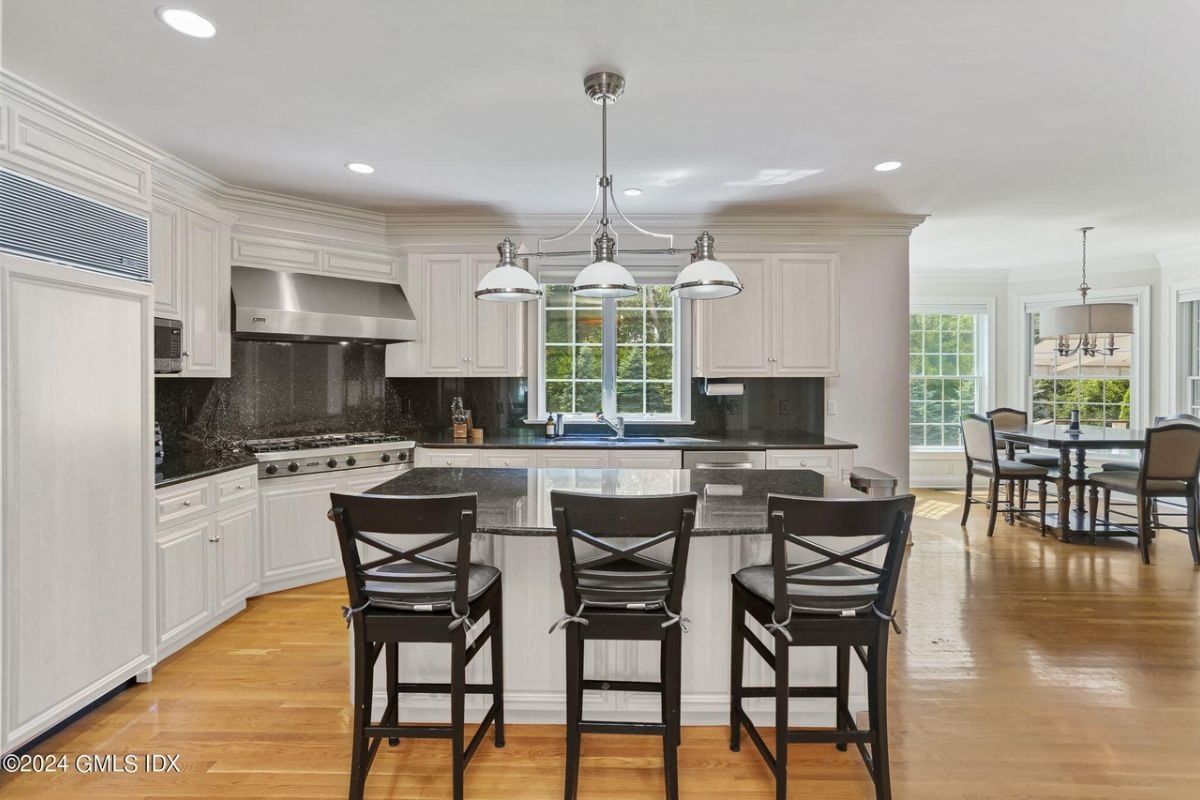 The kitchen features a center island, chairs, countertops, cabinets, and kitchen appliances.