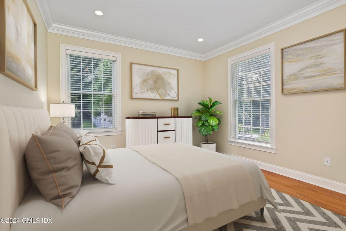The bedroom is furnished with a bed, cabinet, windows, and paintings.