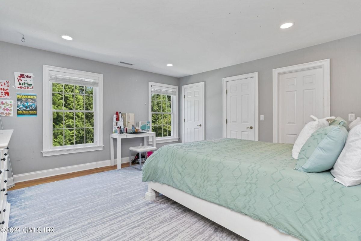 The bedroom is furnished with a bed, windows, a rug, and a desk with a chair.