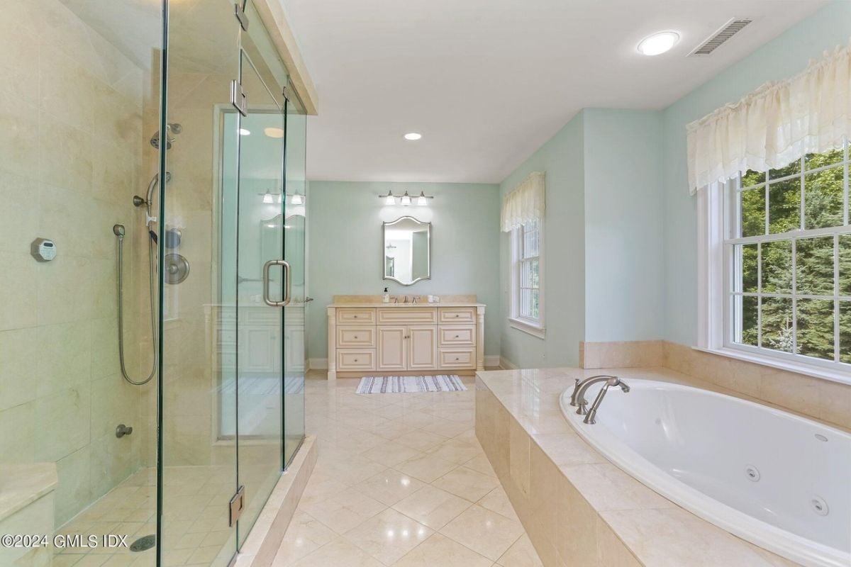 The bathroom is equipped with a vanity, mirror, windows, a shower room, and a bathtub.