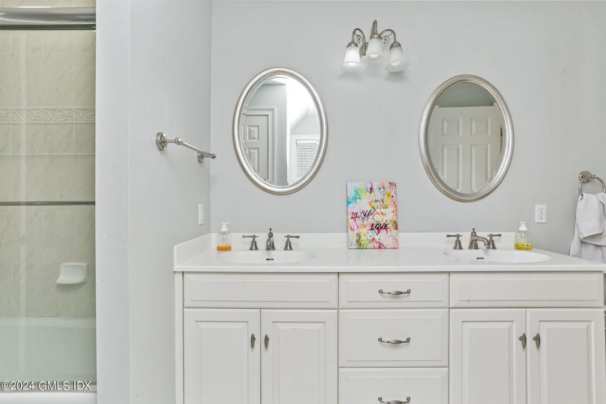 The bathroom includes dual vanities, mirrors, and a cabinet.