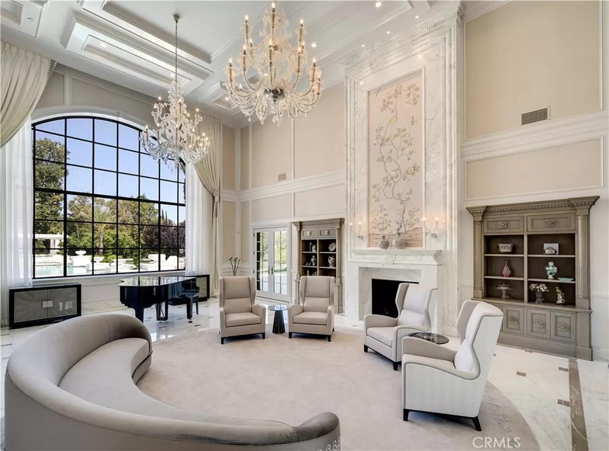 Living room with a piano, coffered ceilings, a chandelier and a fireplace.