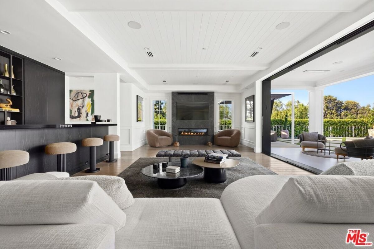 A living room with a TV, fireplace, chairs, couch, center table, and bar.
