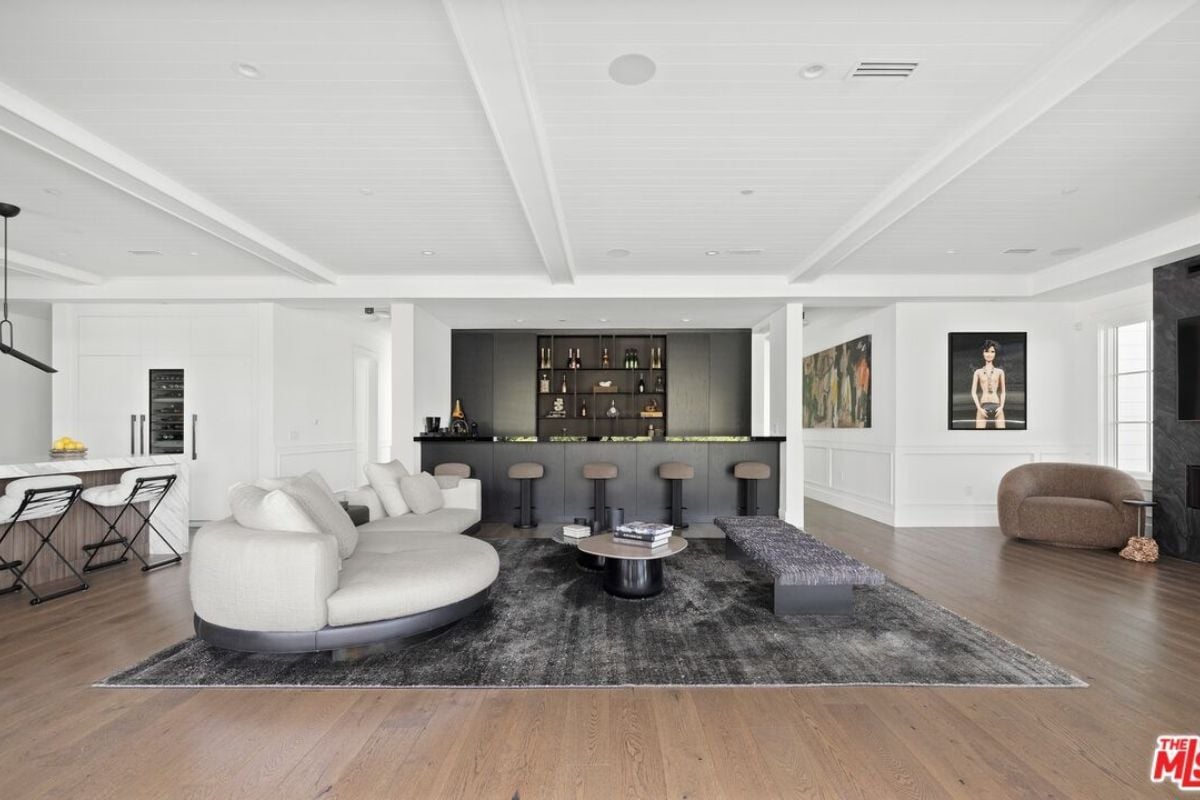 A living room with a TV, fireplace, chairs, couch, center table, and bar.