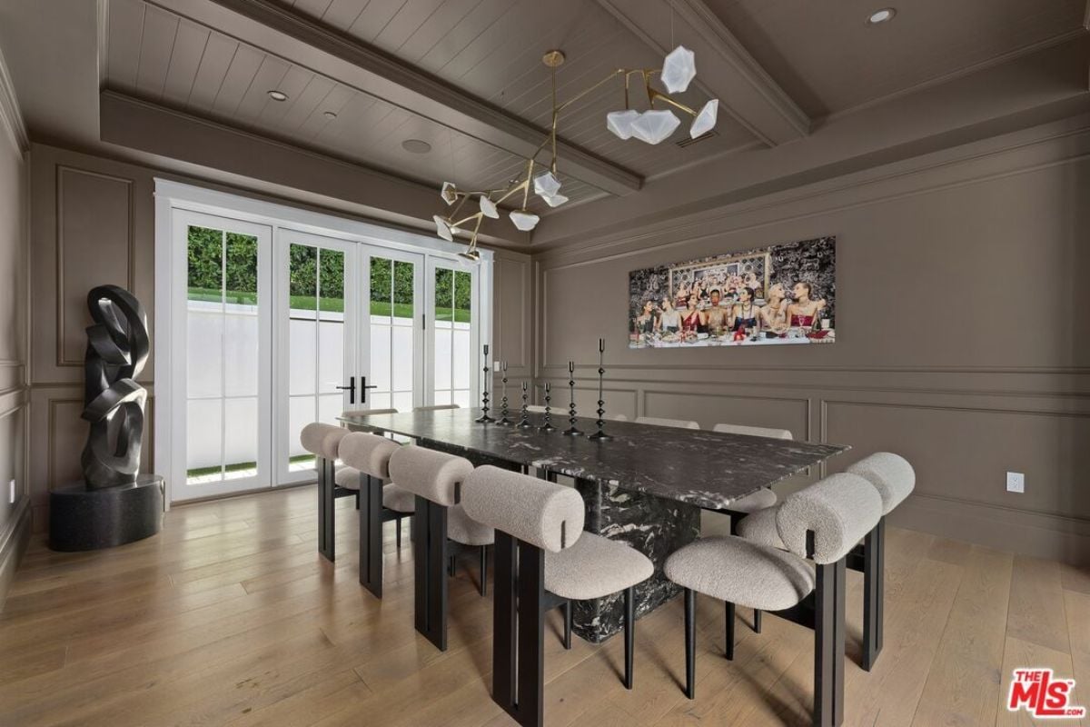 A dining room with a statue, TV, and a dining table surrounded by chairs.