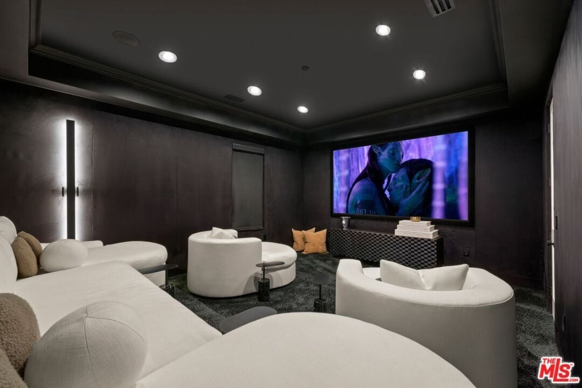 A home theater with black ceilings, black walls, a large screen, and white couches.