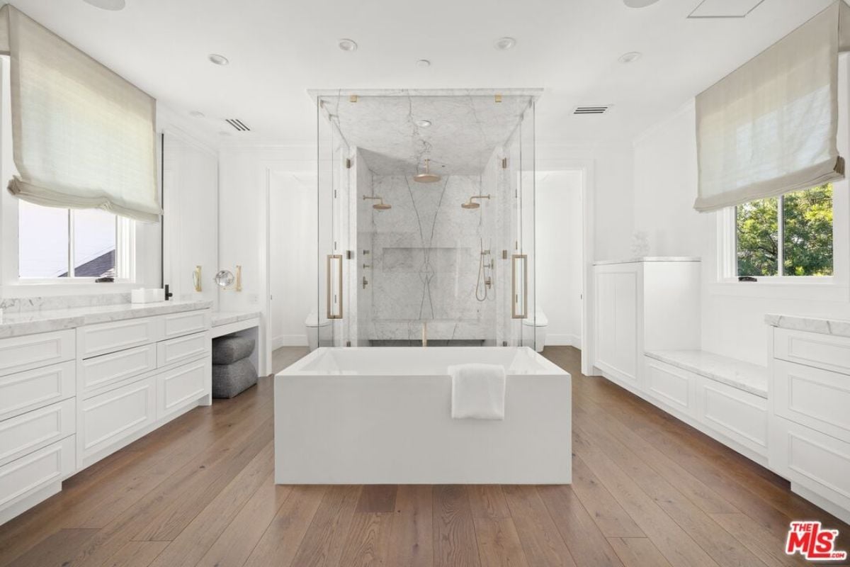 A bathroom with a countertop, cabinets, bathtub, and shower room.