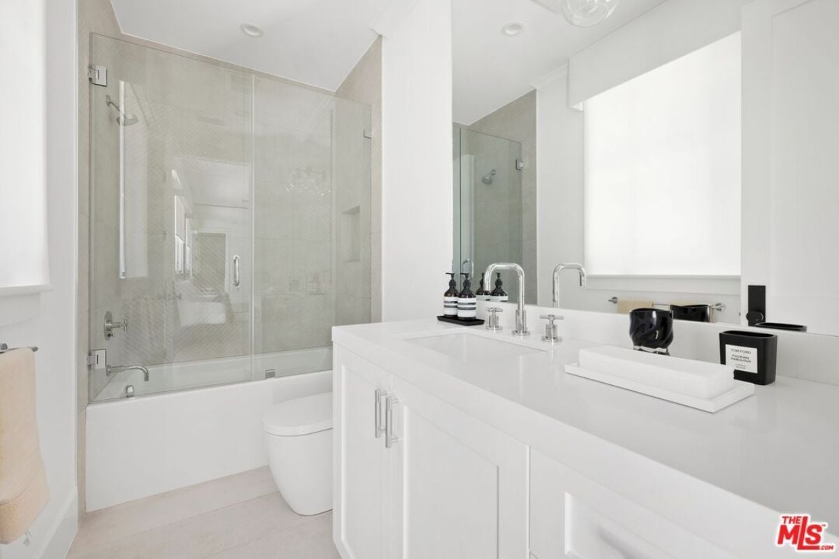 A bathroom with dual vanity, mirror, cabinet, toilet, and bathtub.