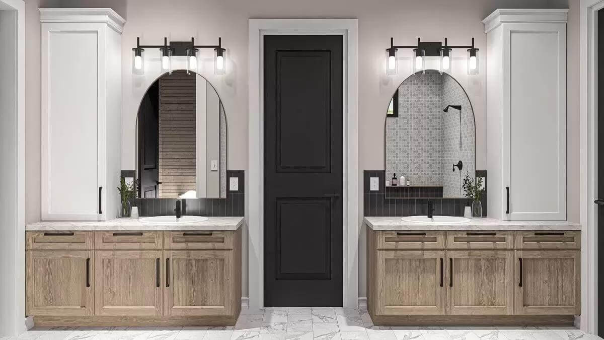 His and her vanities topped with arched mirrors and linen cabinets.