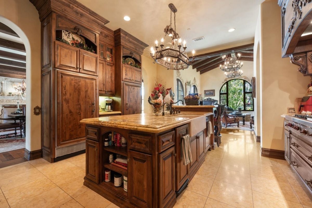 A kitchen with a chandelier, center island, countertop, and cabinets.