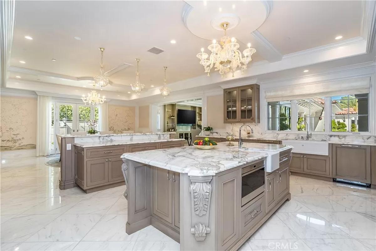 Kitchen with chandeliers, custom cabinetry, counter breakfast bar and a center island prep area.