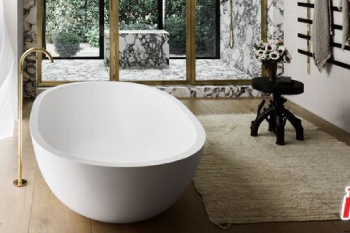 A bathroom with a rug, a table with a vase, and a bathtub.
