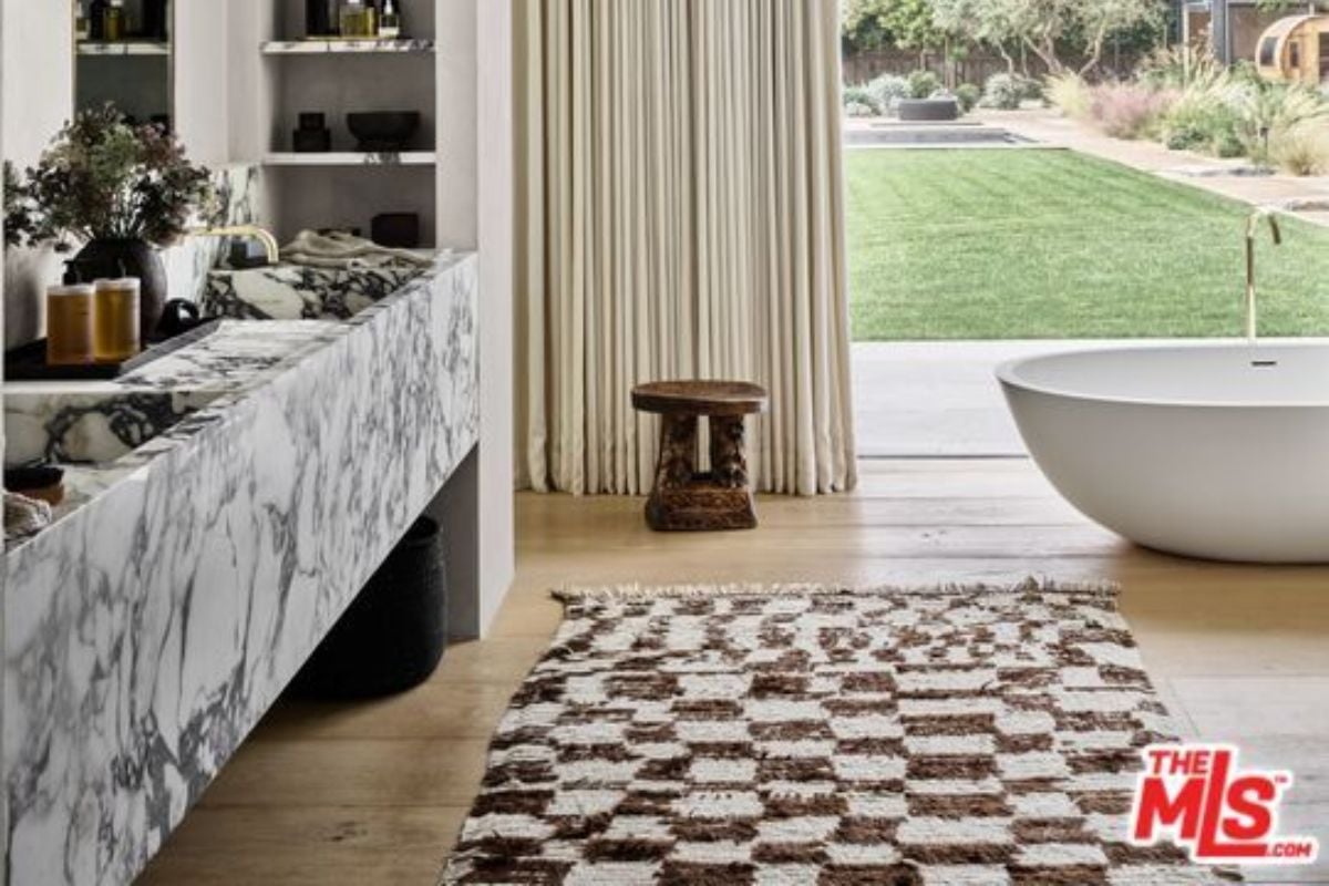 A bathroom with a marble countertop, rug, and bathtub.