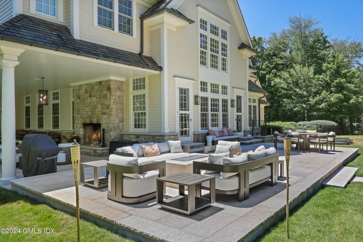 An outdoor living space with couches, chairs, a coffee table, and a dining table surrounded by chairs.